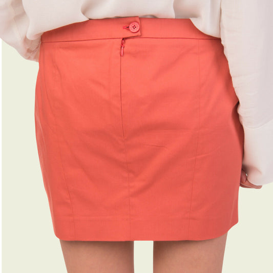 Person wearing a coral skirt on a plain background