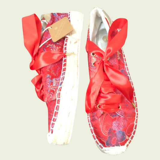 Red floral-patterned sandals with large bows on a light background