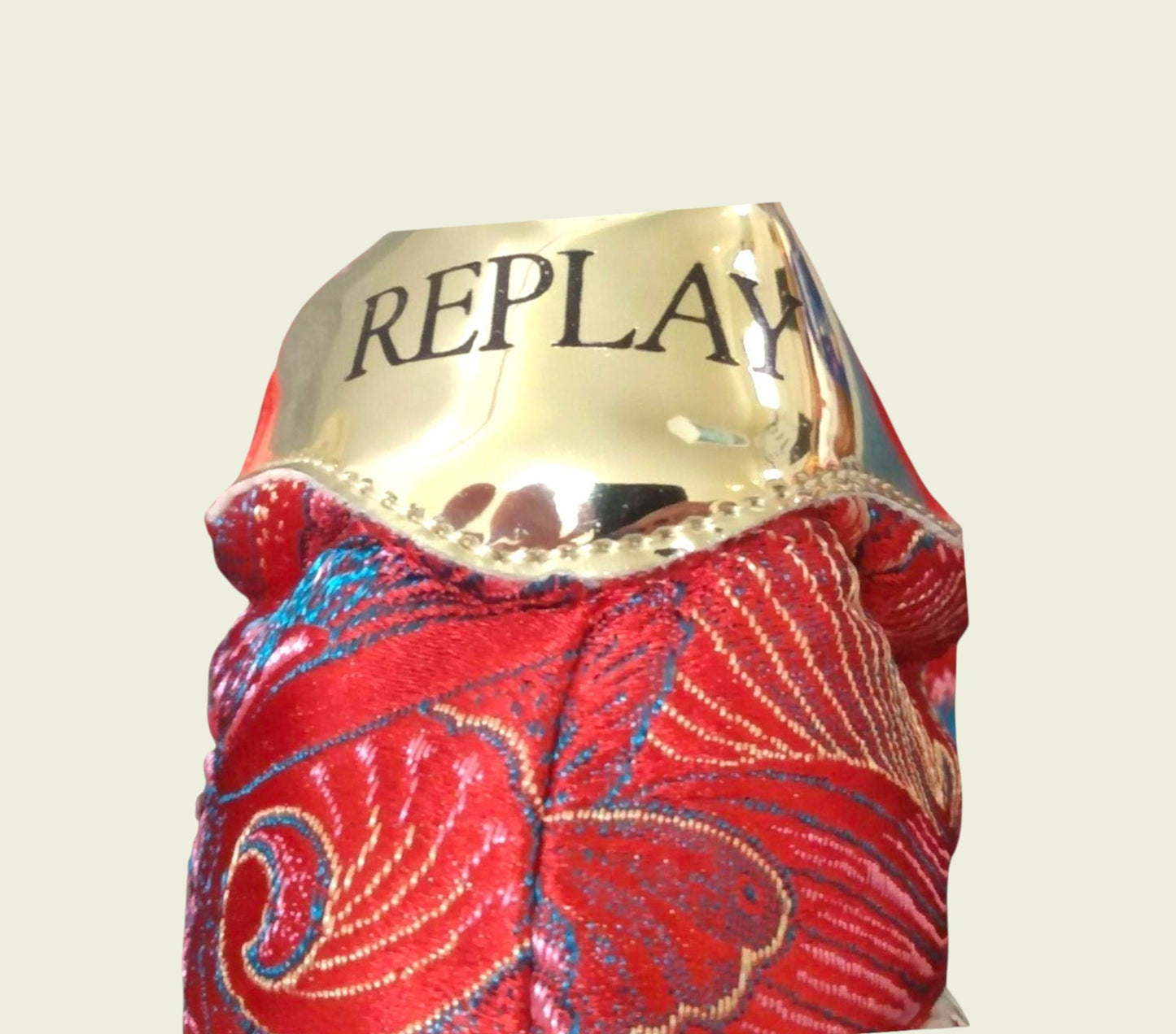 Red fabric with gold 'REPLAY' label on a beige background