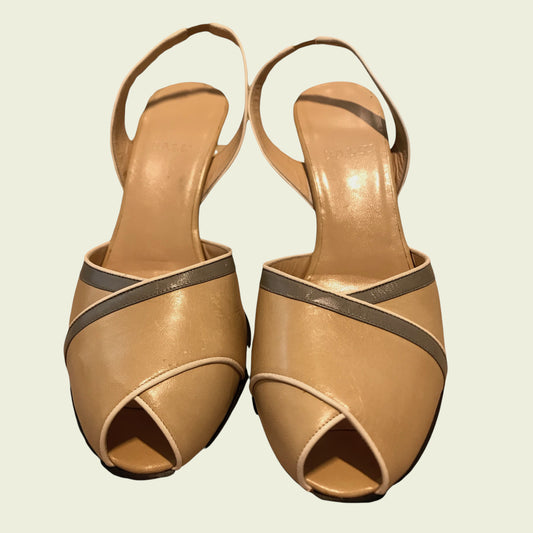 Pair of tan high-heeled sandals with brown straps on a light background