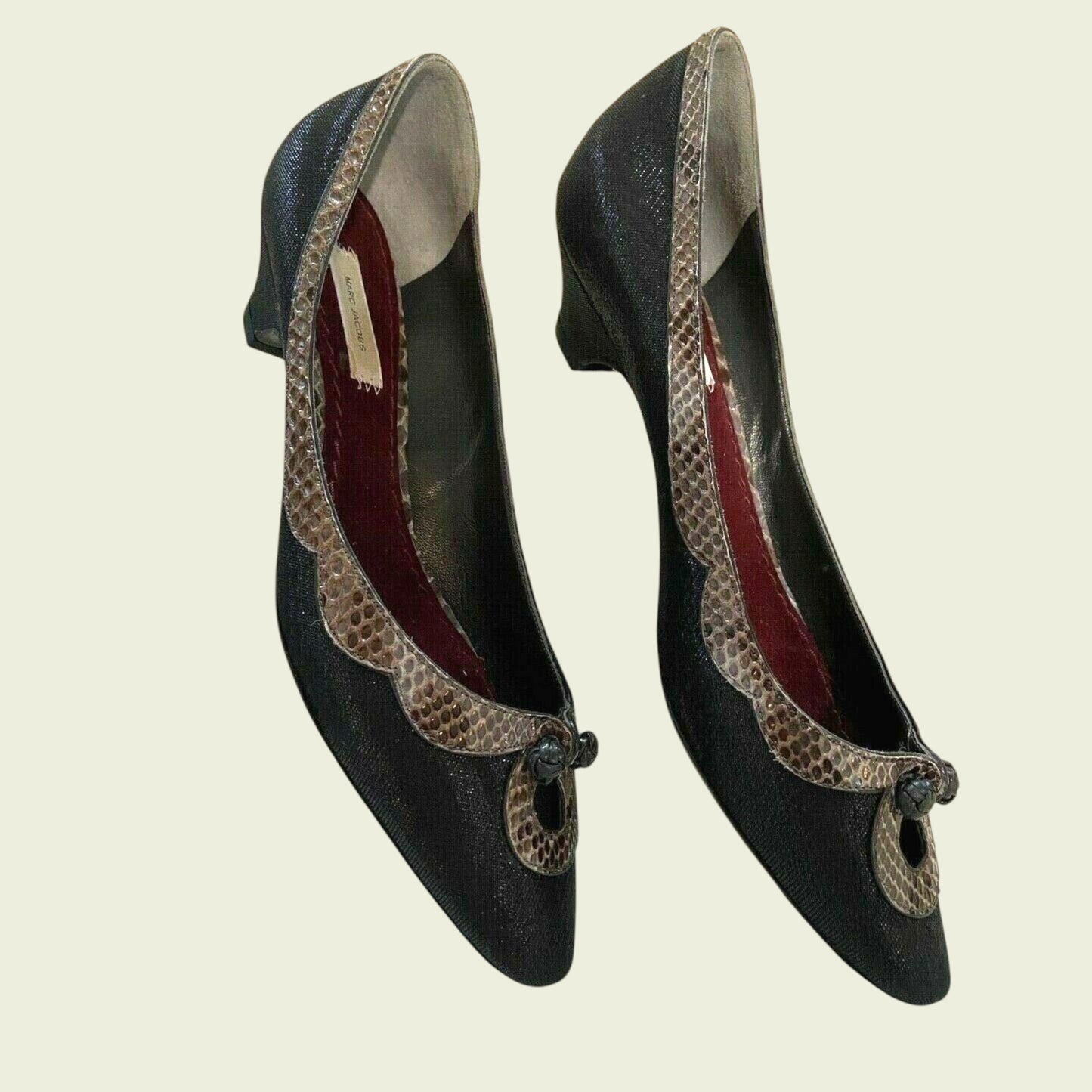 Pair of black shoes with decorative straps on a beige background