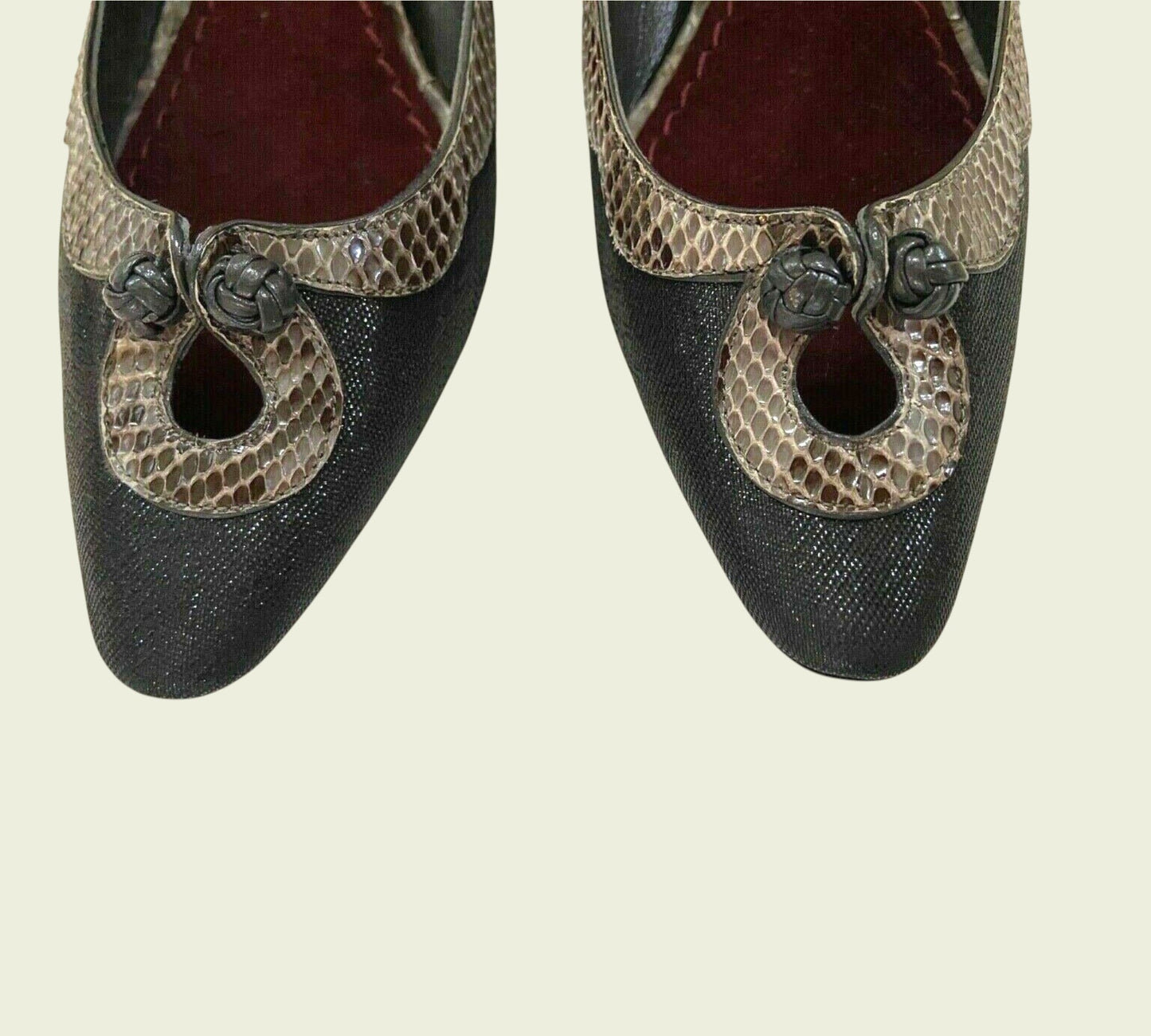 Pair of black shoes with snake skin pattern on a beige background