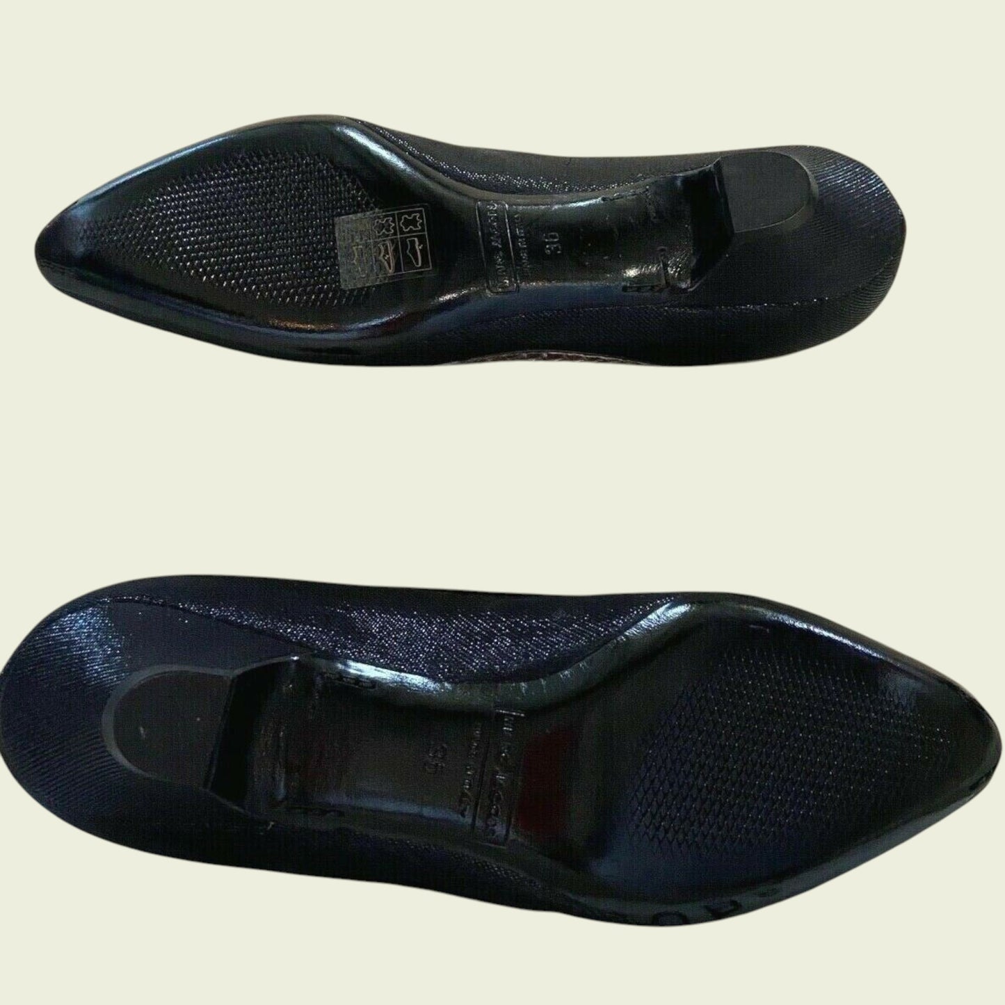 Two black shoe insoles on a beige background