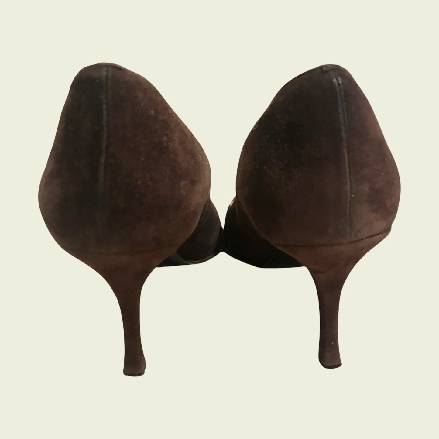 Pair of brown high-heeled shoes on a beige background