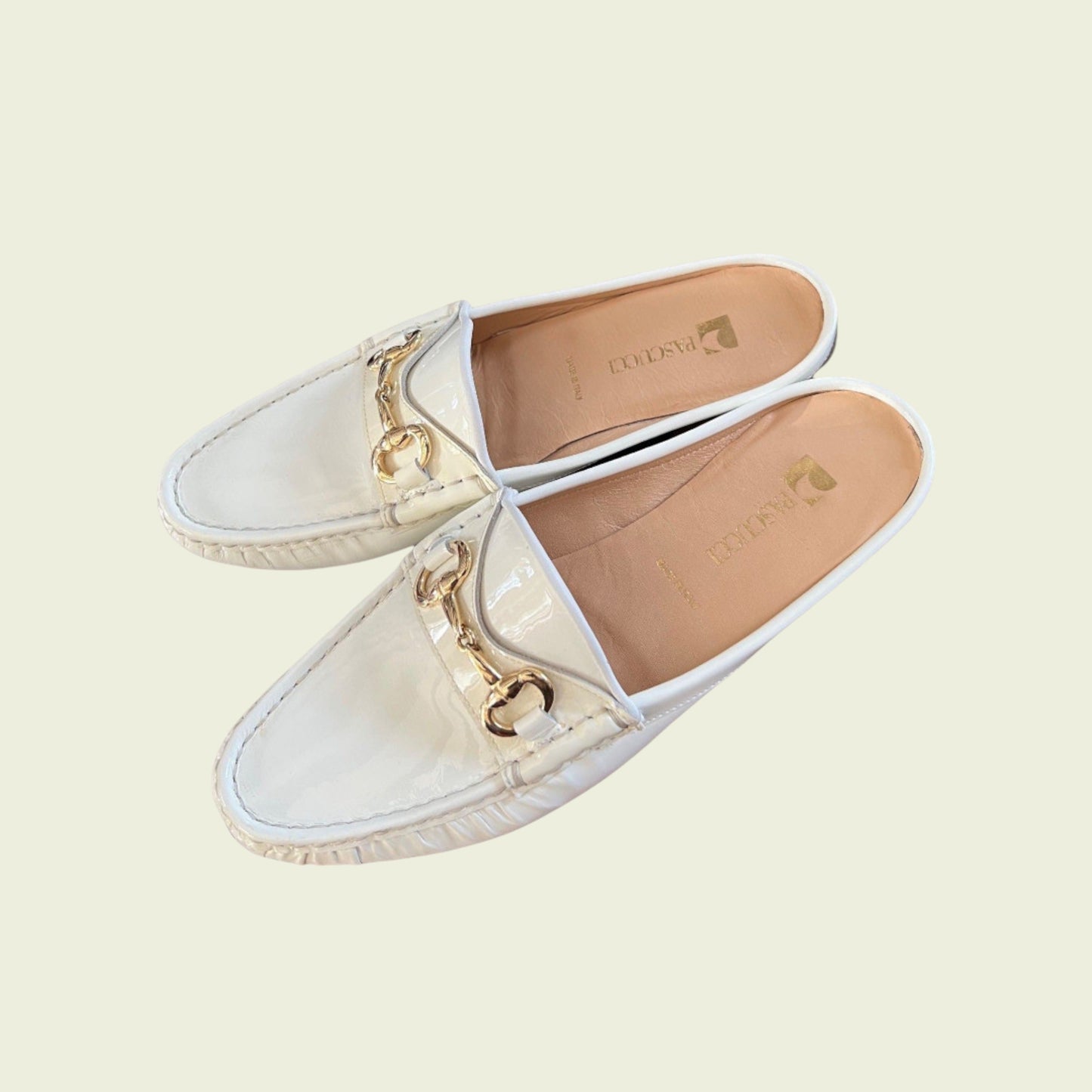 White loafers with gold chain detail on a light beige background