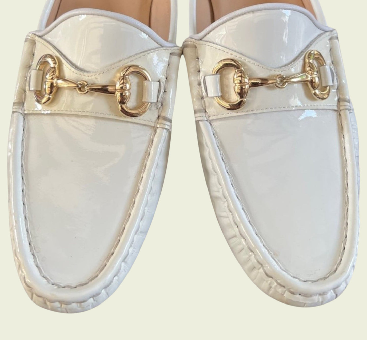 White loafers with gold accents on a light beige background