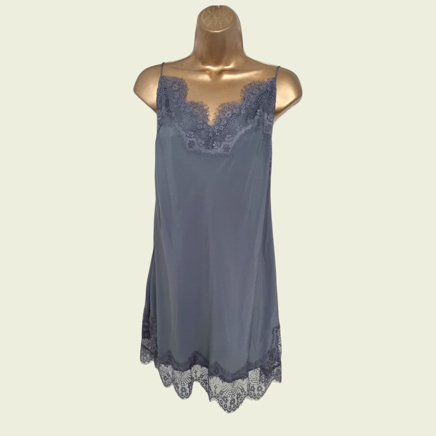 Gray slip dress with lace details on a mannequin against a beige background