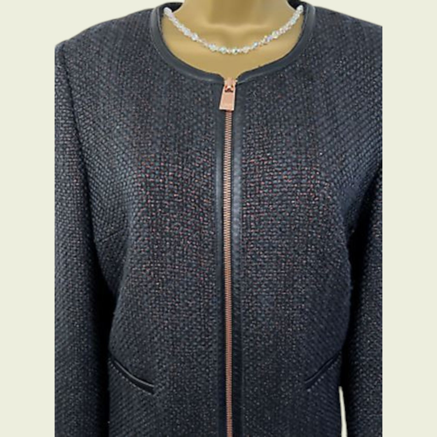 Dark textured jacket with a zipper on a mannequin against a beige background