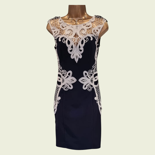 Navy dress with white lace details on a mannequin against a beige background