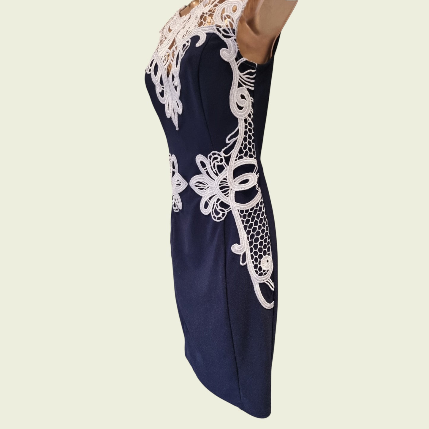 Navy blue dress with white lace detailing on a beige background