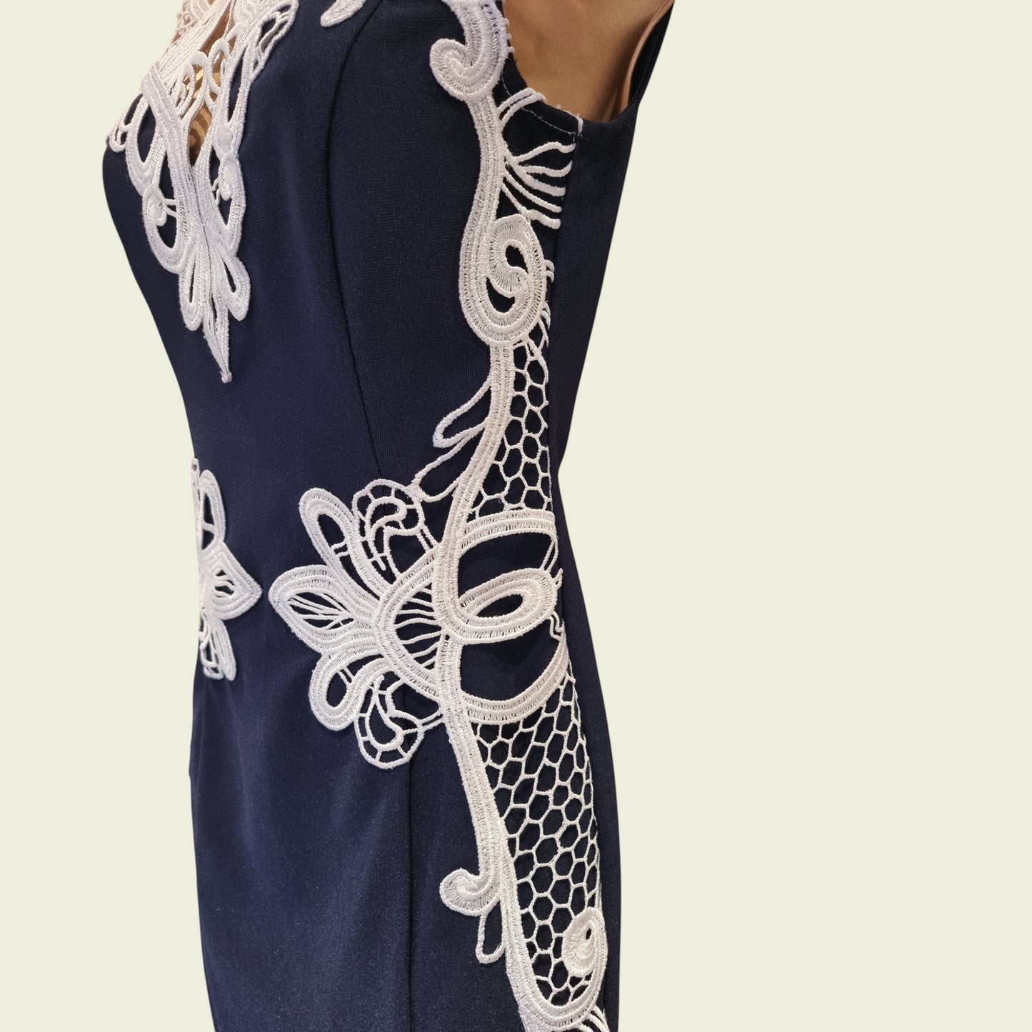 Navy dress with white lace detailing on a beige background