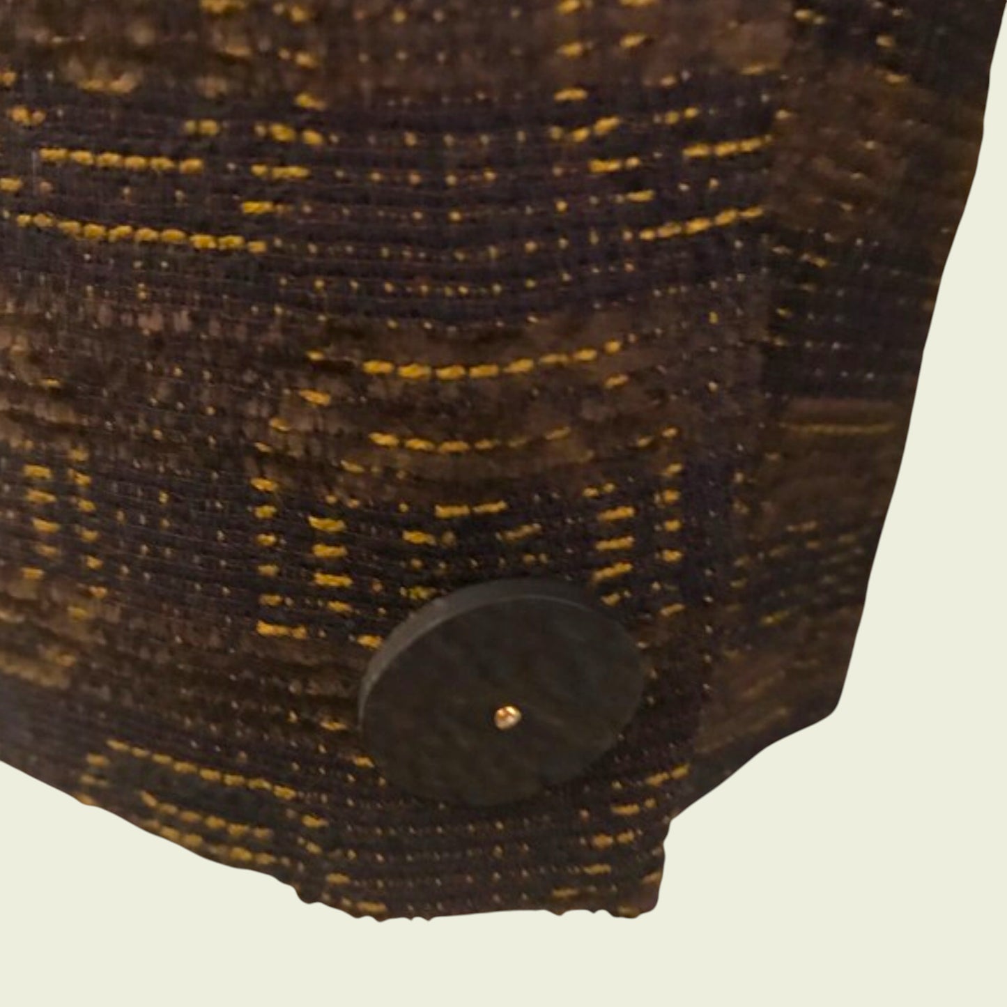Close-up of a textured plum fabric with a button on a beige background