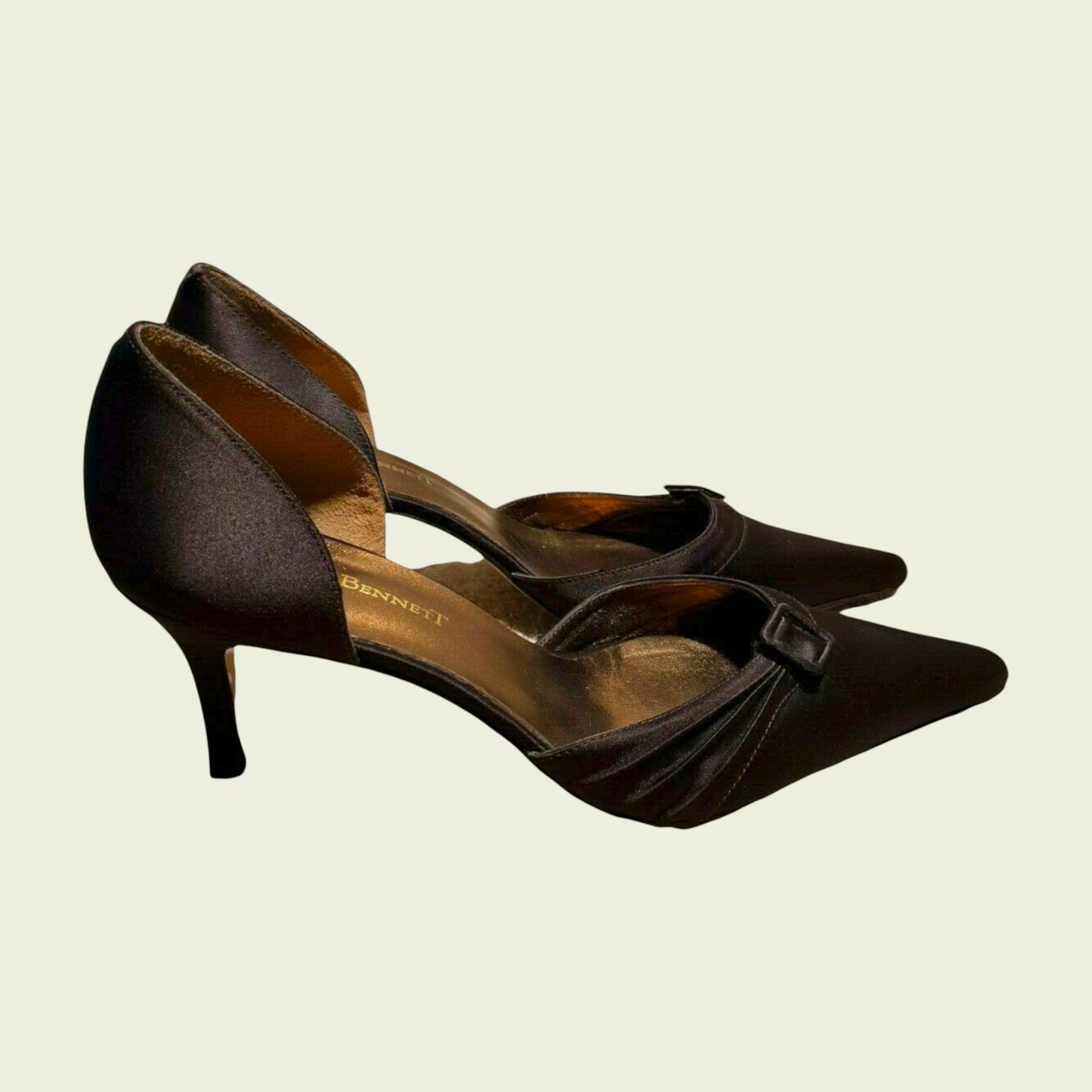 Pair of brown high-heeled shoes with a bow on a beige background