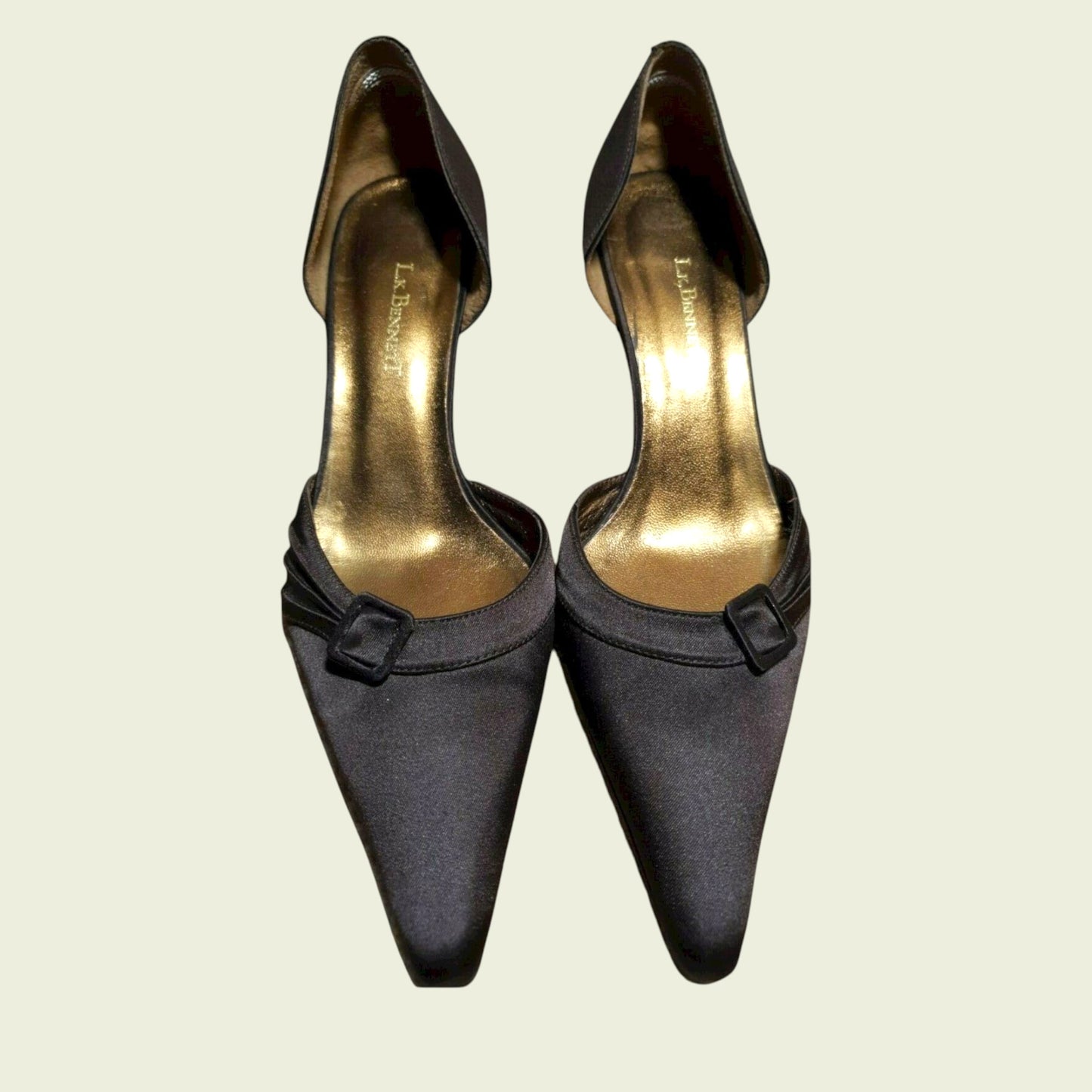Pair of brown high-heeled shoes with gold soles on a beige background