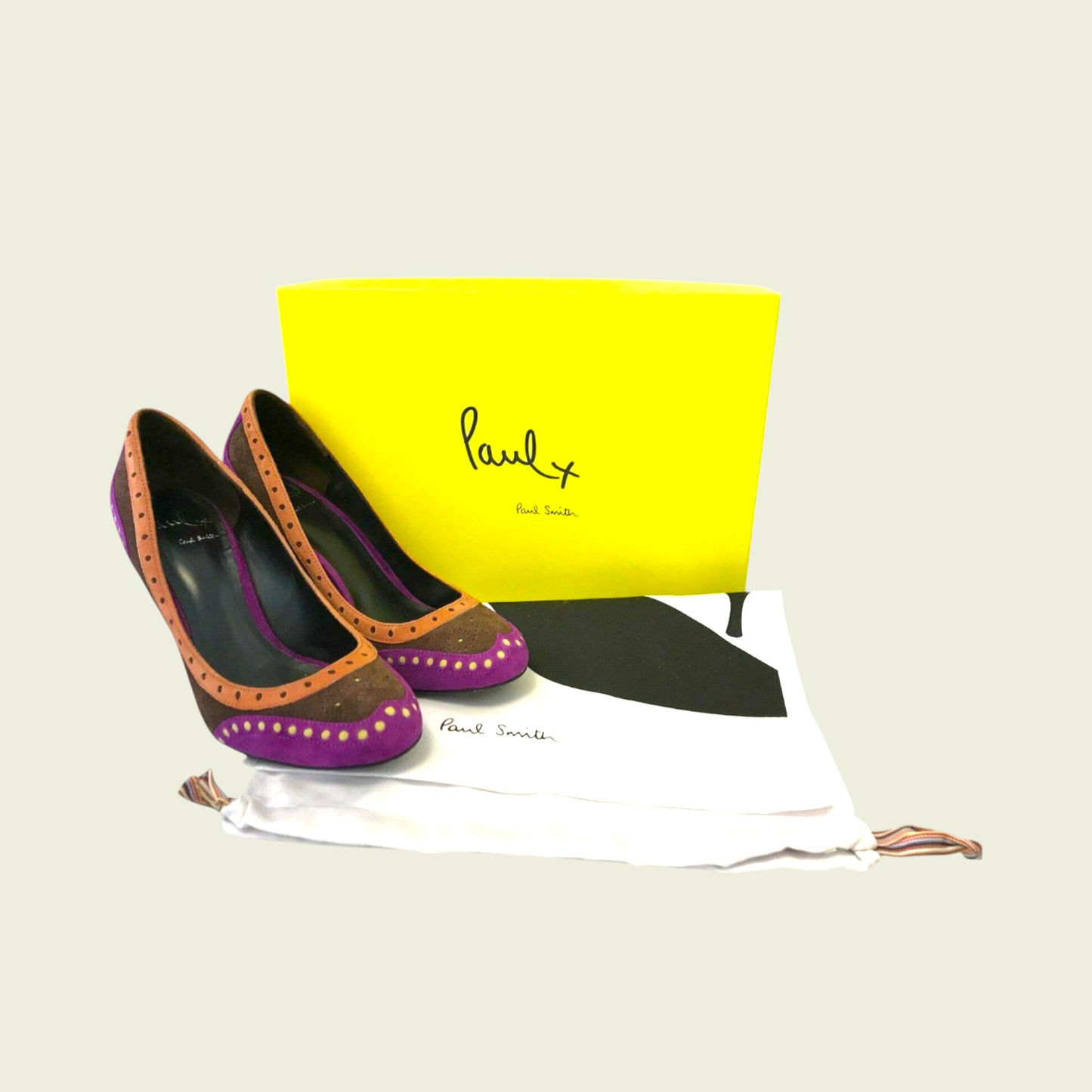 Pair of high-heeled shoes with a yellow box featuring a brand logo on a light background