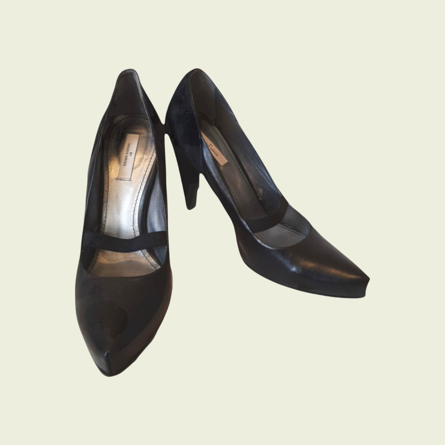 Pair of black high-heeled shoes on a beige background