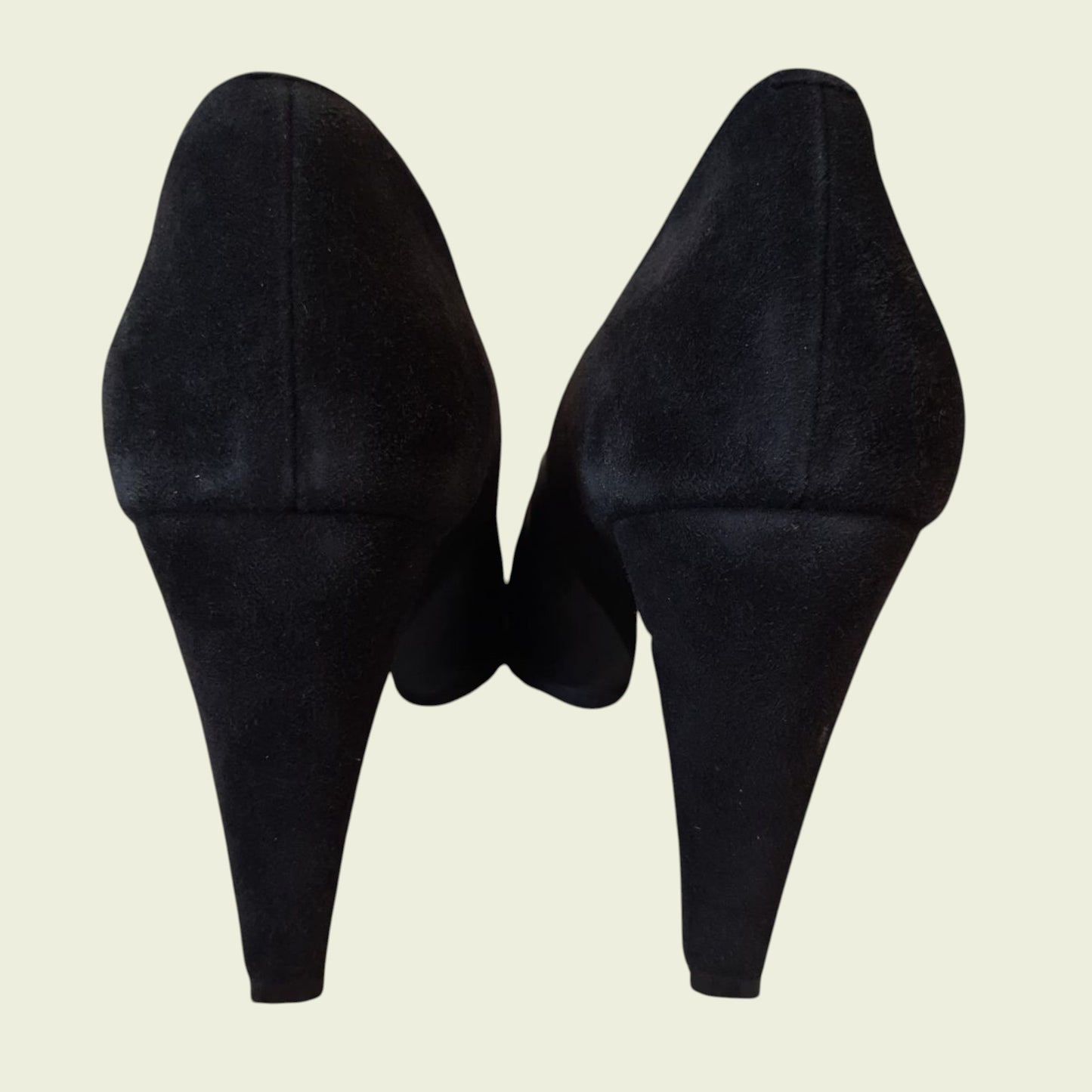 Pair of black high-heeled shoes on a beige background