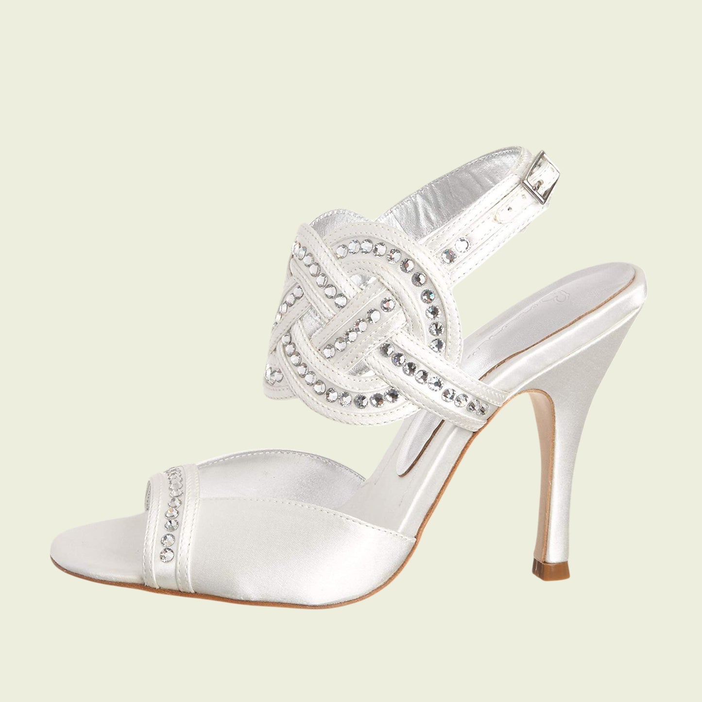 White high-heeled shoe with decorative elements on a light beige background