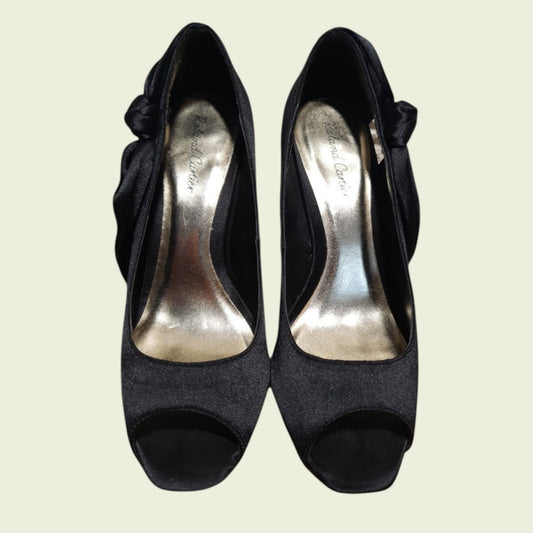 Black high-heeled shoes with open toes on a light beige background