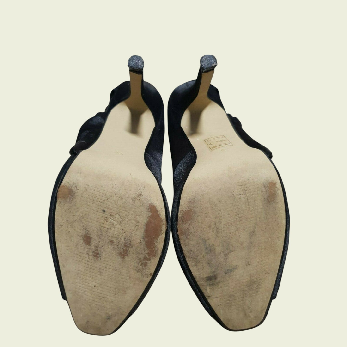 Pair of black shoes with worn soles on a beige background