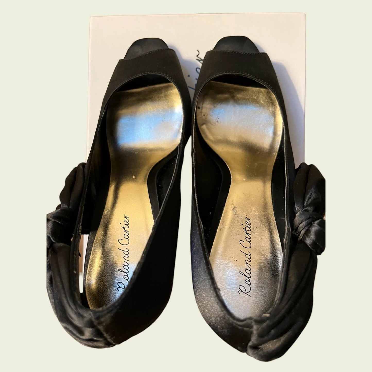 Black high-heeled shoes with 'Roland Cartier' branding on a light background