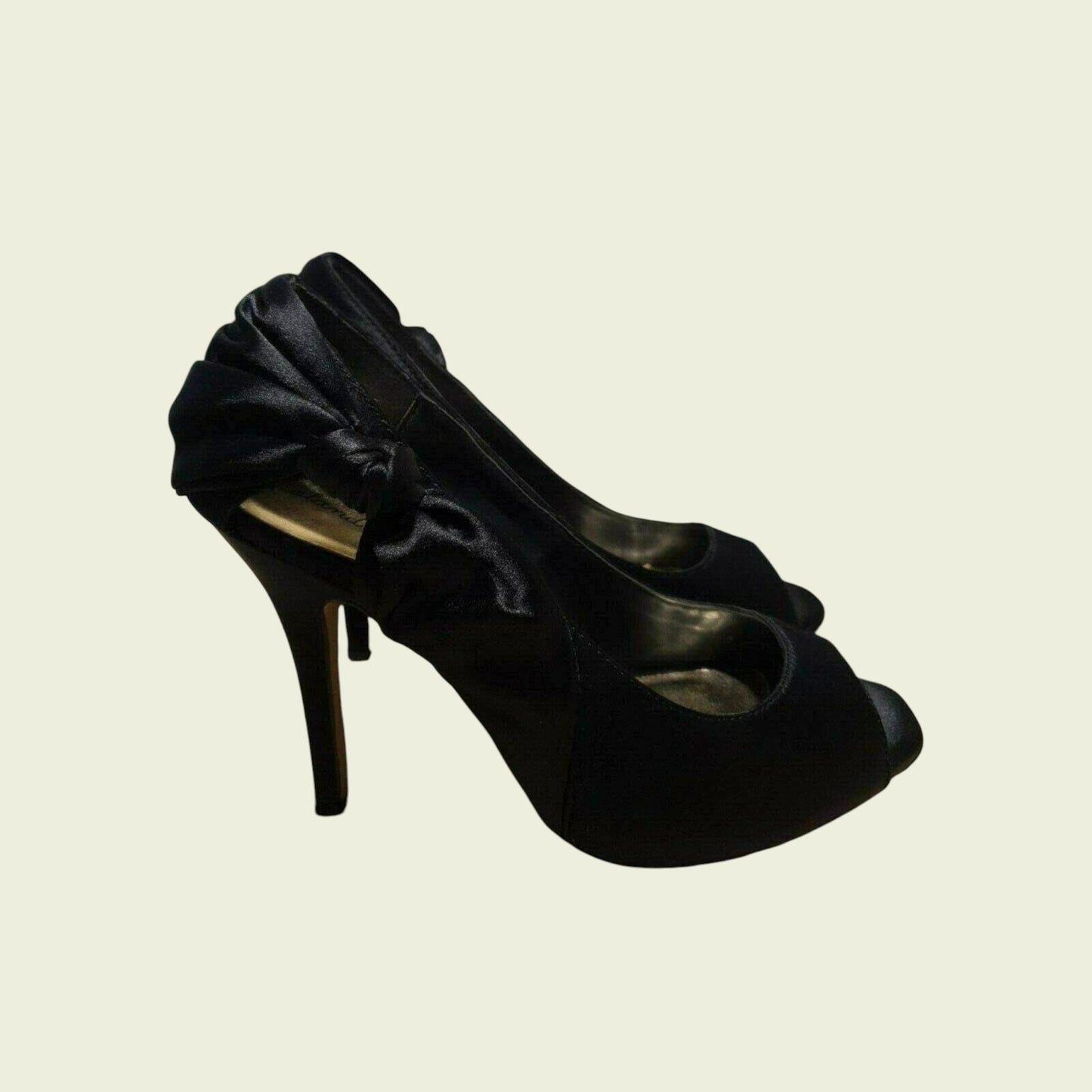 Black high-heeled shoe with bow detail on a beige background