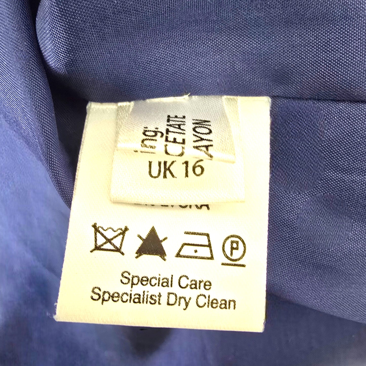 Clothing label with care instructions on a blue fabric background