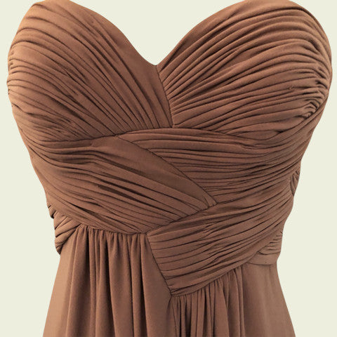 Brown strapless dress with pleated details on a beige background