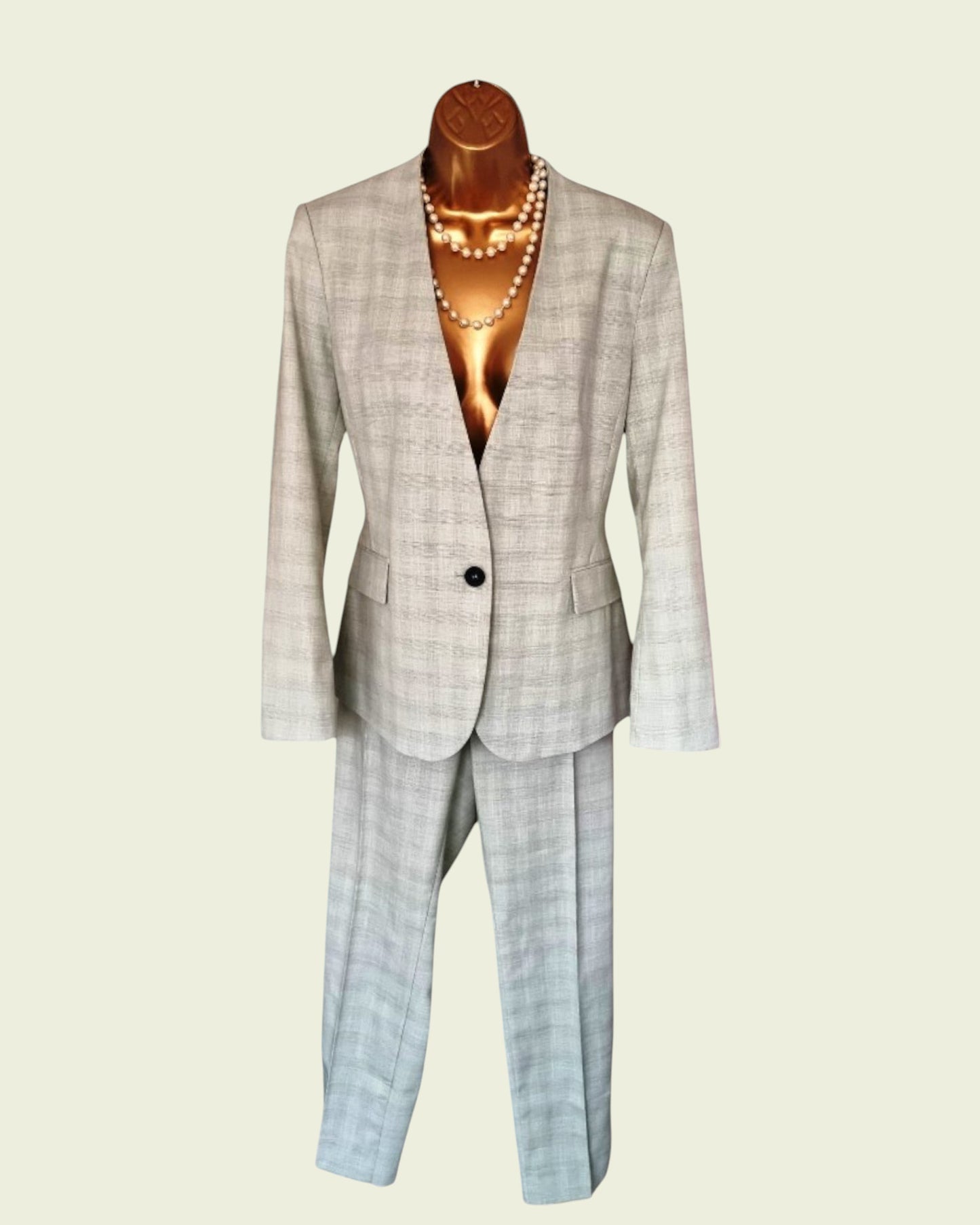 Plaid suit on a mannequin with a pearl necklace against a beige background