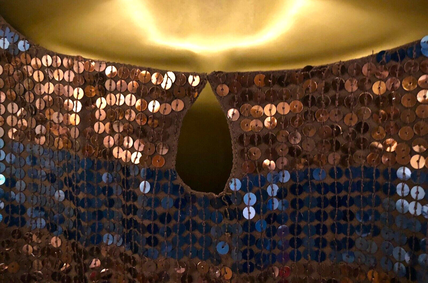 Close-up of a sequined fabric with a gold circular object on top