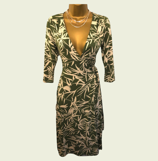 Green dress with leaf pattern on a mannequin against a beige background