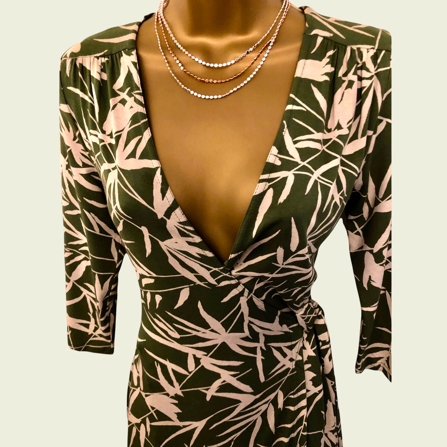 Green and pink patterned dress on a mannequin with a beige background