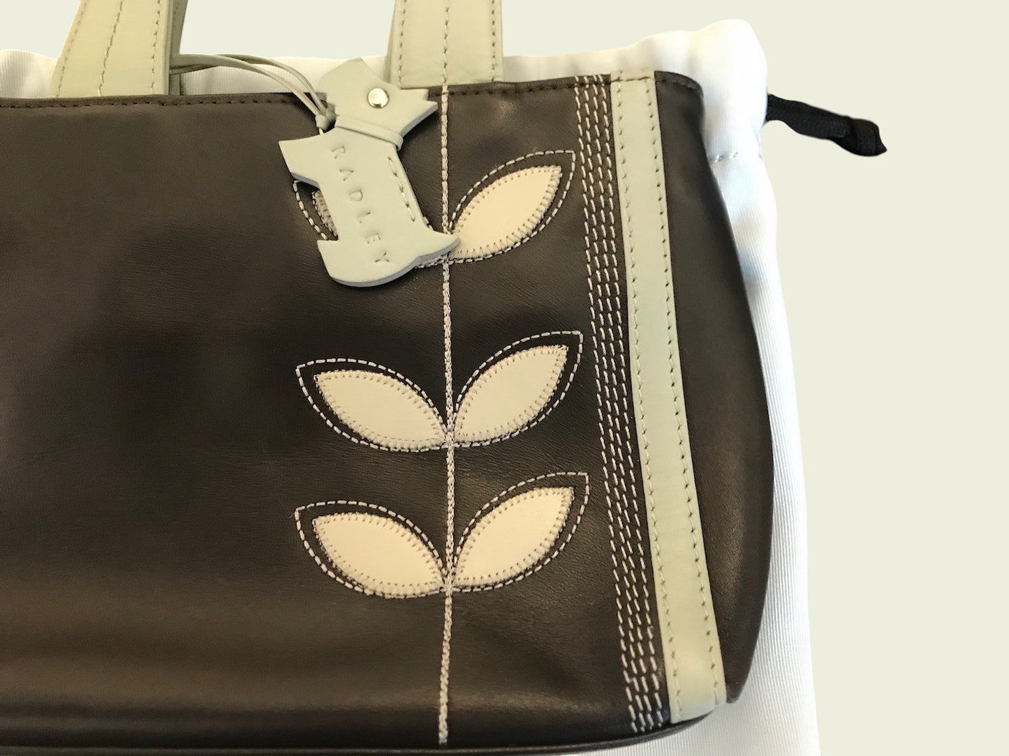 Brown handbag with leaf designs and a matching keychain on a white background