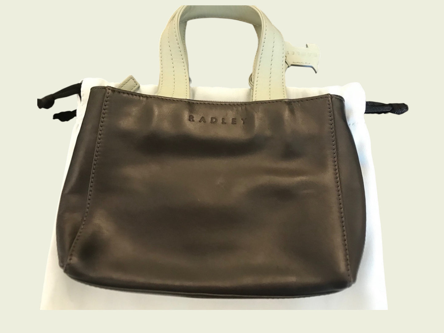 Brown handbag with beige handle on a white background