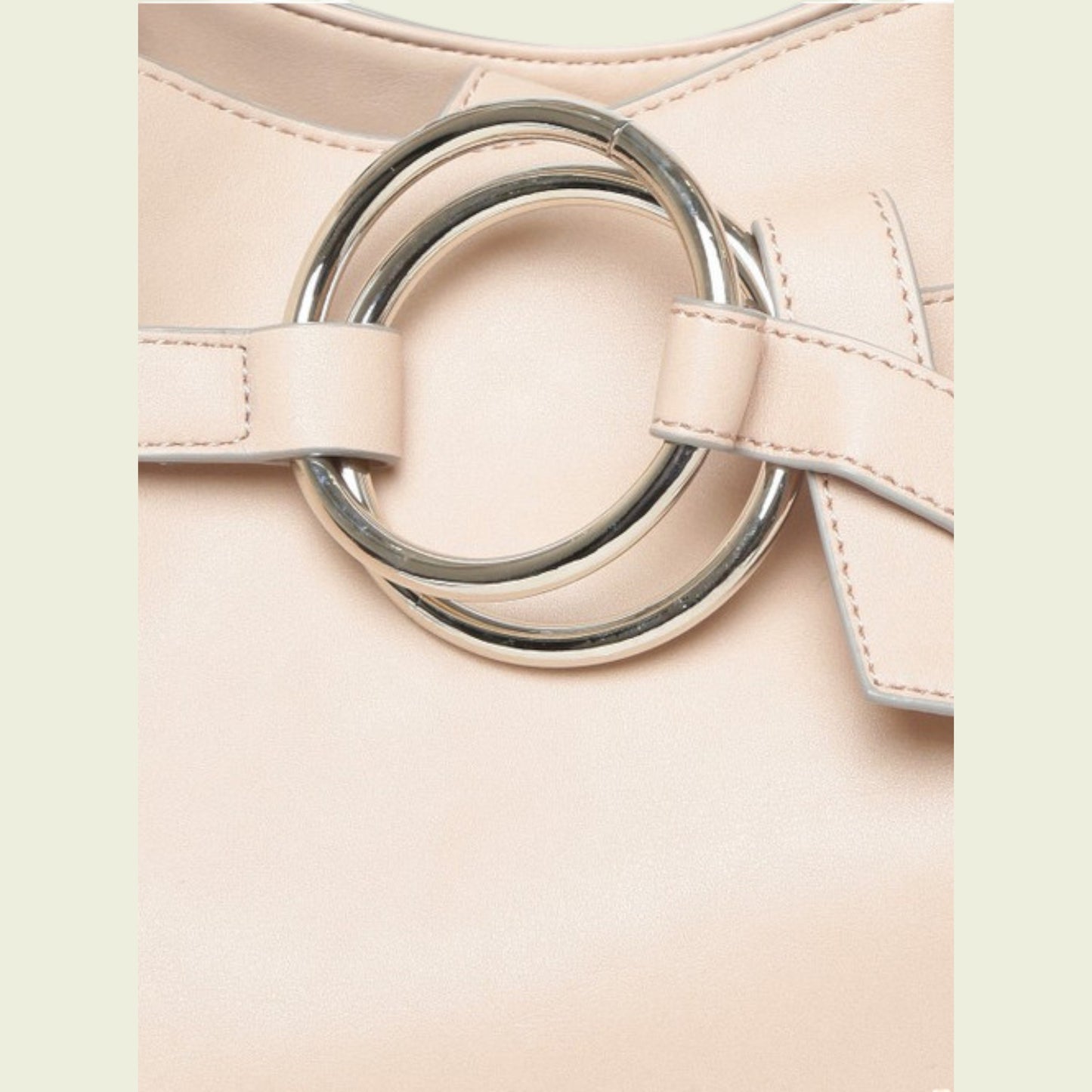 Close-up of a pink handbag with a silver ring buckle on a light background