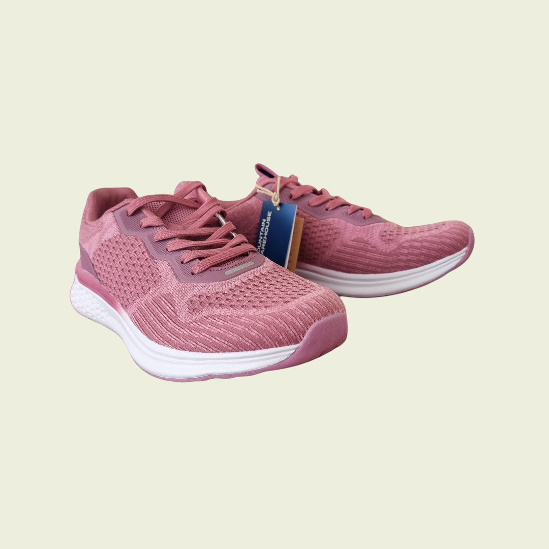Pink running shoes with a white sole on a light beige background