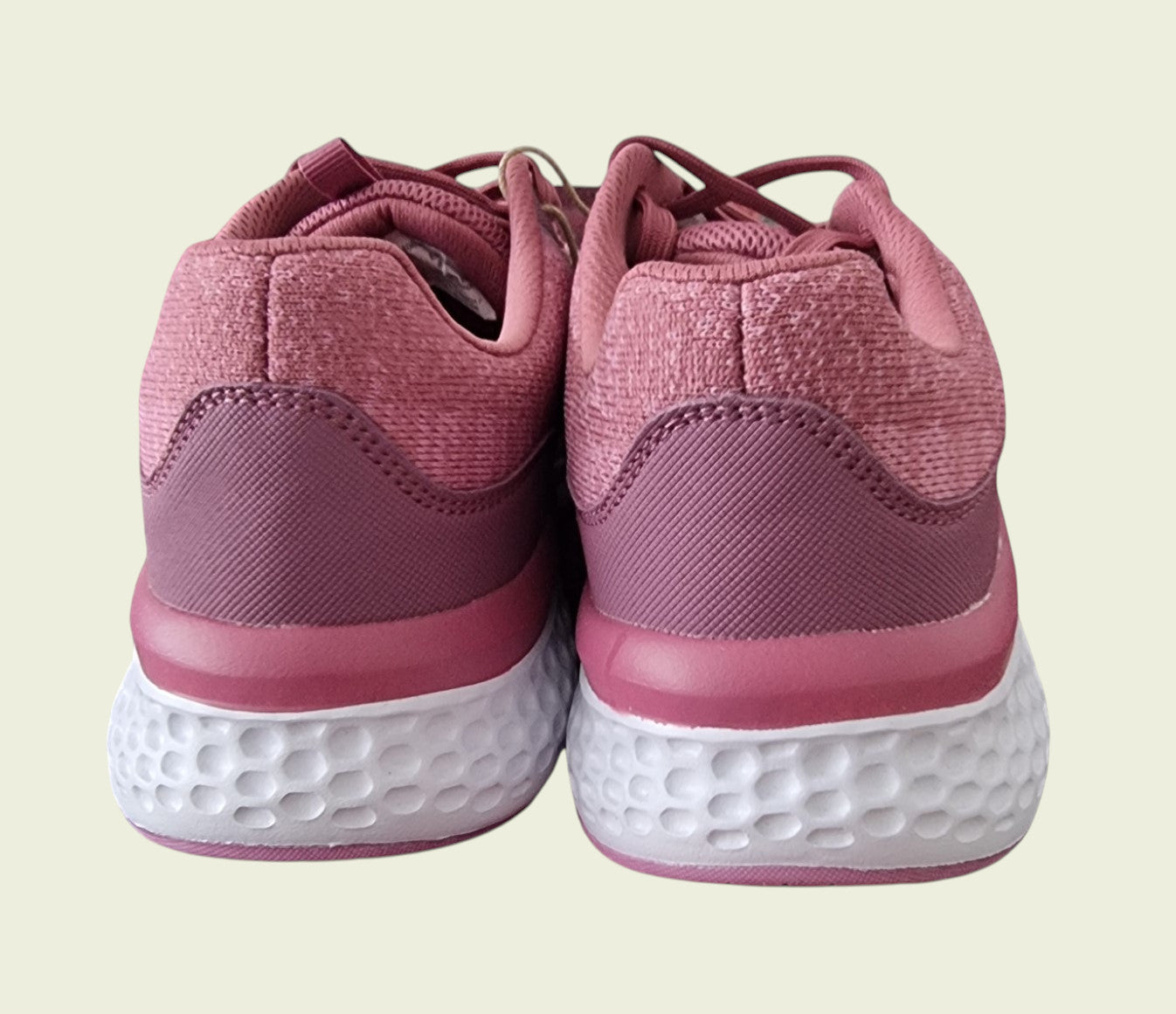 Pink sneakers with white soles on a beige background
