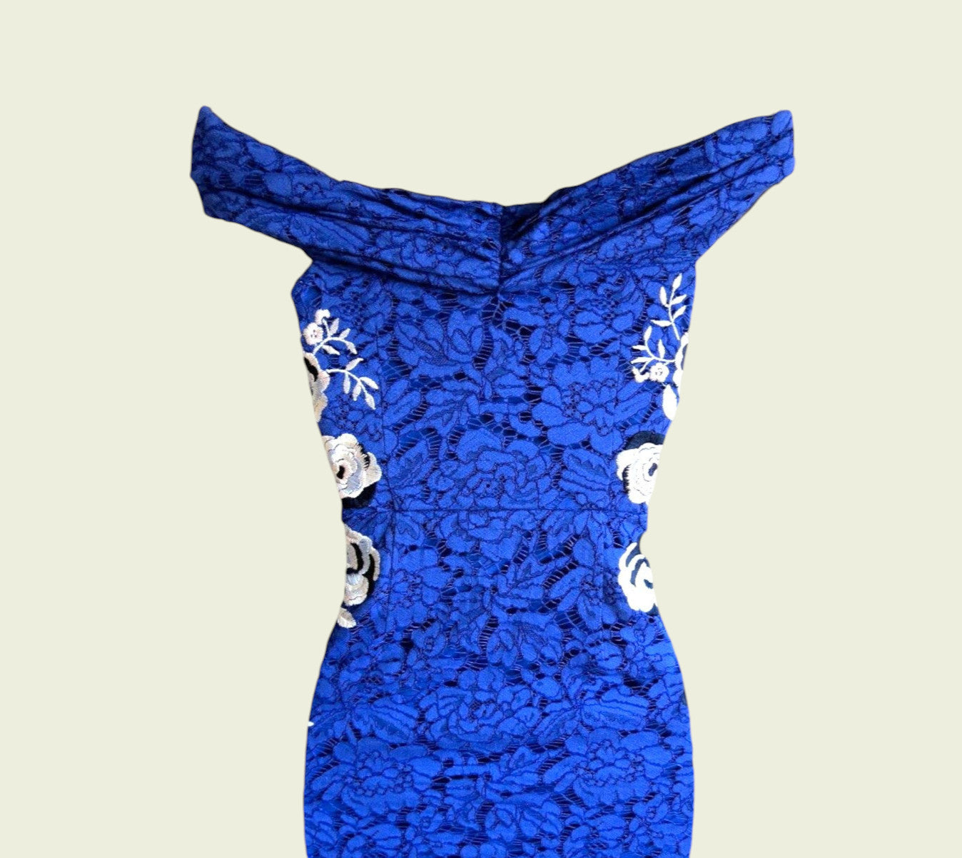 Blue lace dress with floral embellishments on a beige background