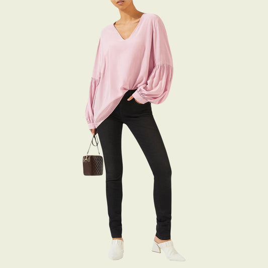 Person wearing a pink blouse and black pants on a beige background