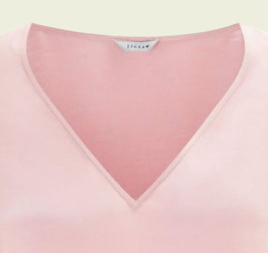 Close-up of a pink garment with a brand label on a light green background