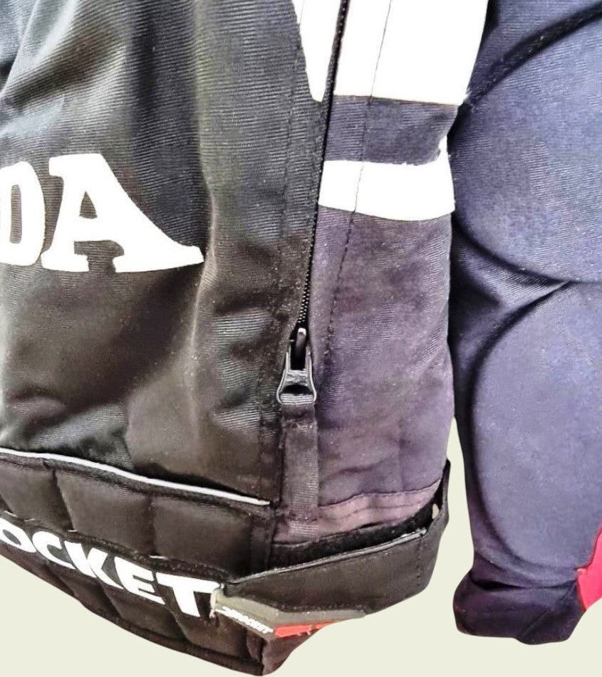 Close-up of a black motor cycle jacket with visible branding on a neutral background