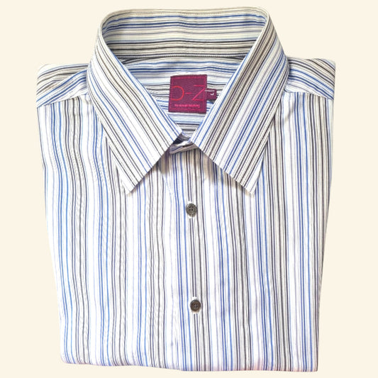A folded long-sleeve button-up dress shirt with vertical blue, gray, and black stripes on a white base, featuring a pointed collar and a pink neck label.