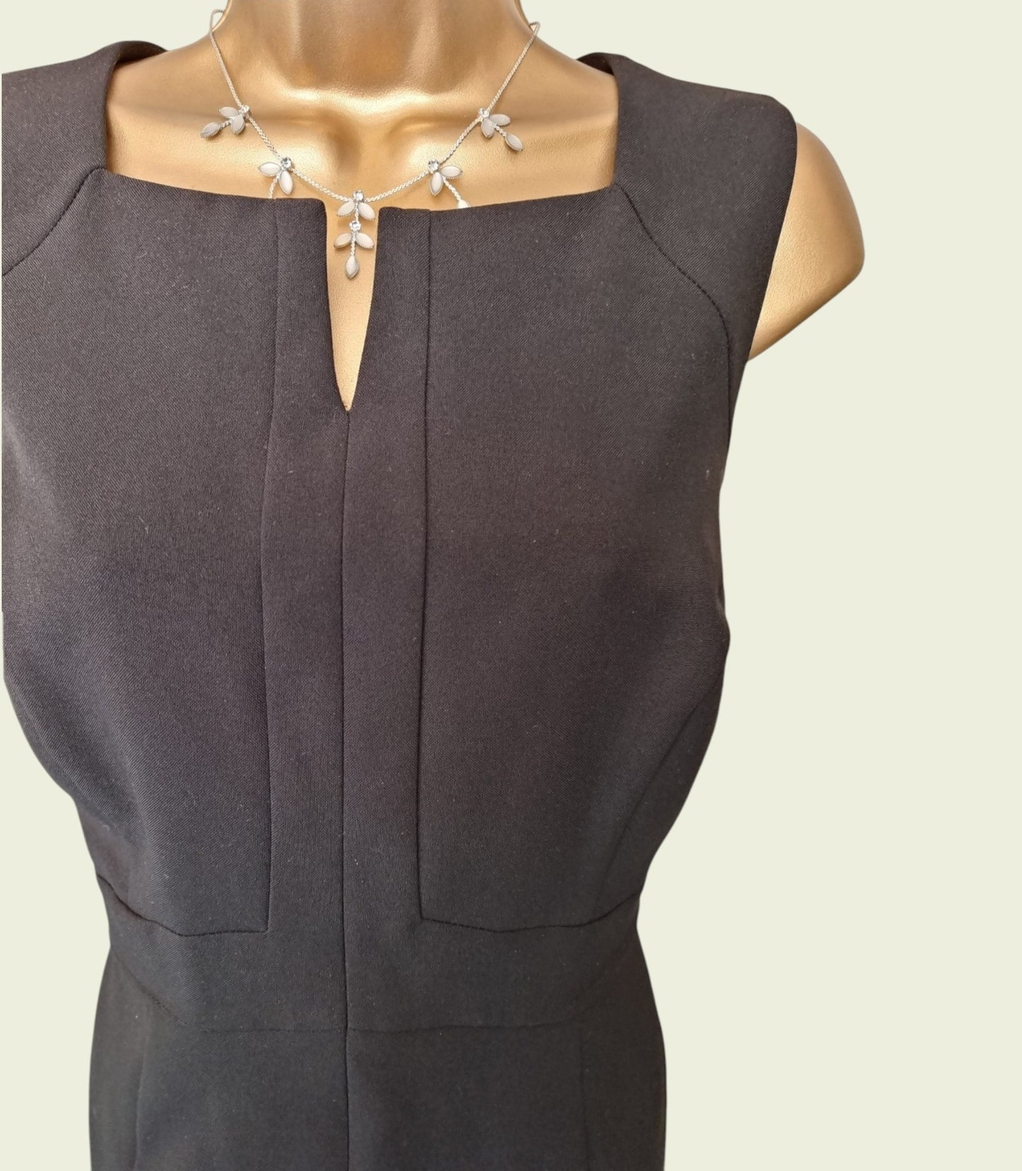 black sleeveless dress on a mannequin with a plain background