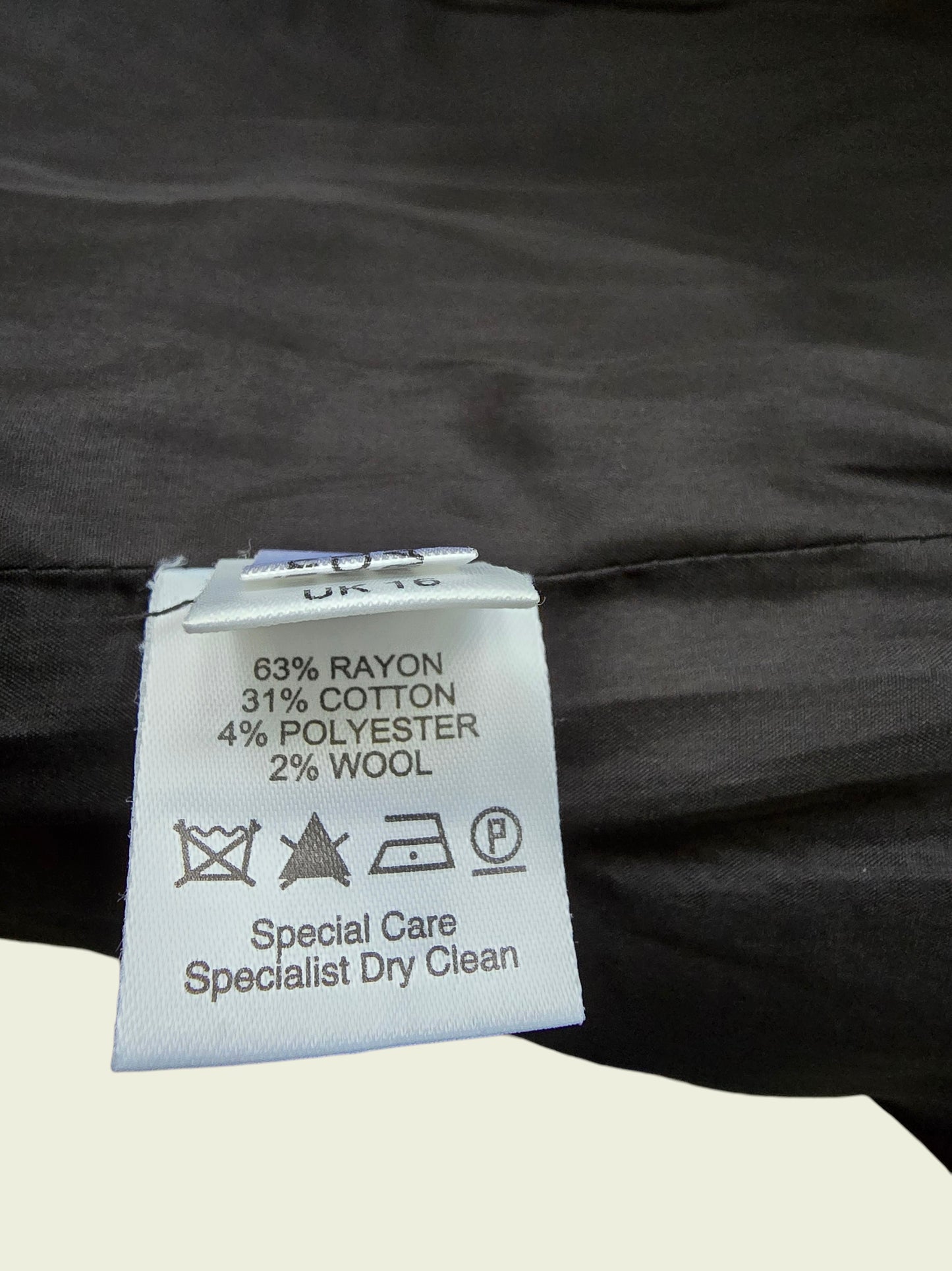 Clothing label with fabric composition and care instructions on a black garment.