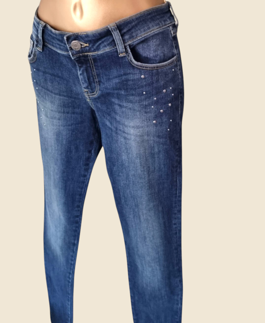 Blue jeans with decorative elements on a beige background