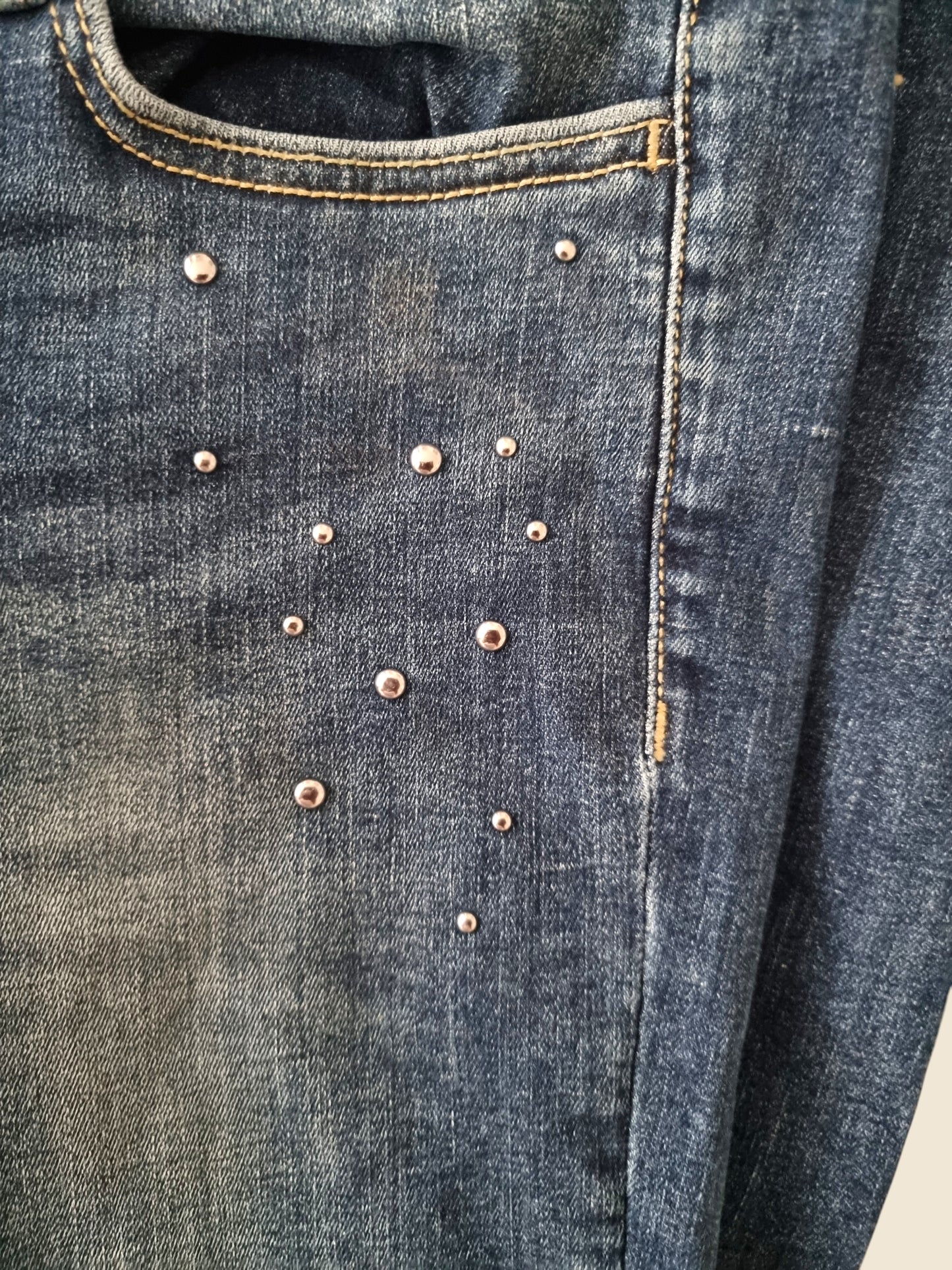 Close-up of blue denim fabric with decorative studs.
