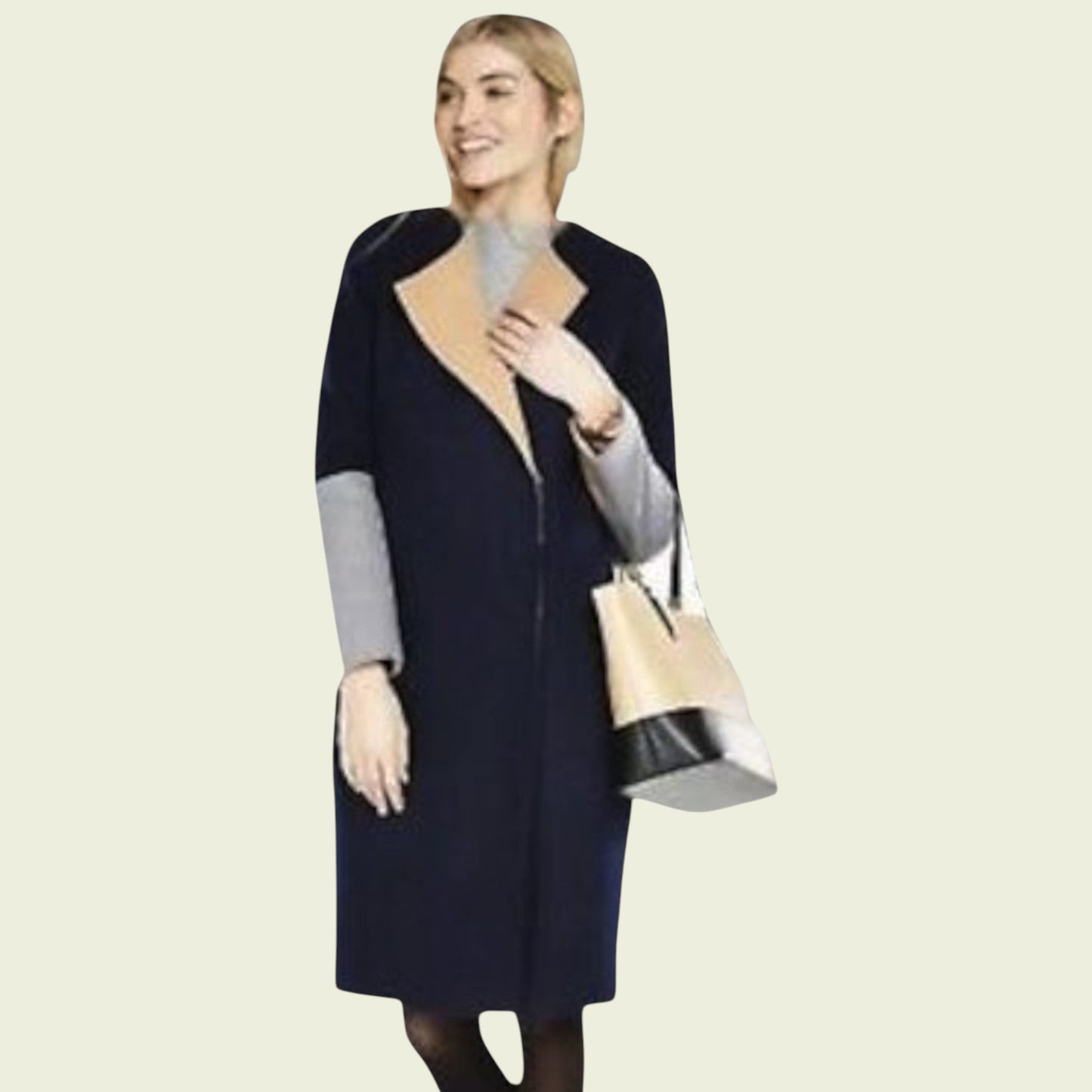 Woman wearing a navy blue coat with gray sleeves, holding a beige handbag on a beige background