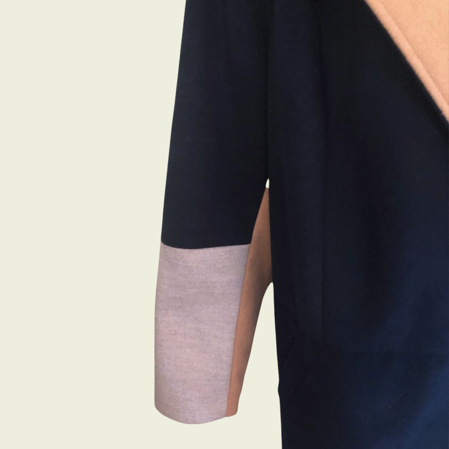 Close-up of a black garment with a pink sleeve on a beige background