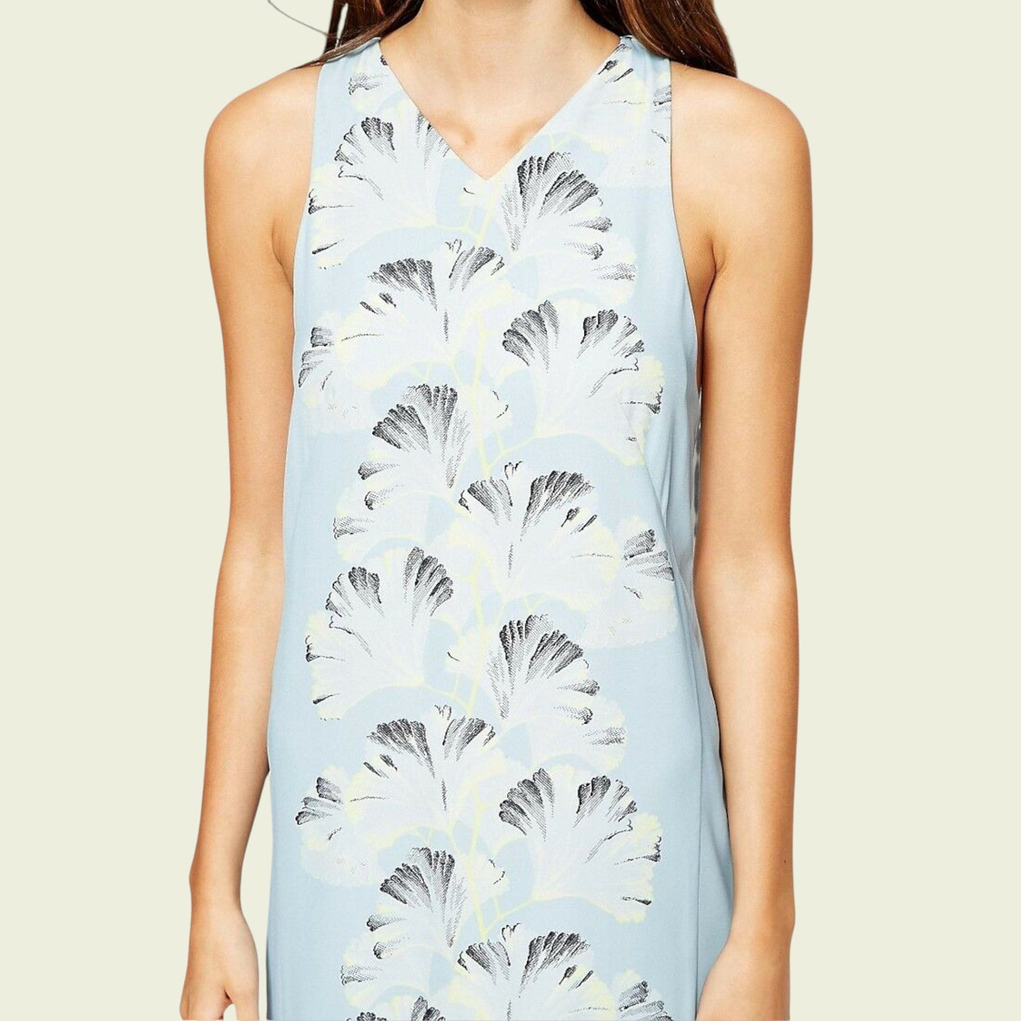 Light blue sleeveless dress with floral pattern worn by a person on a beige background