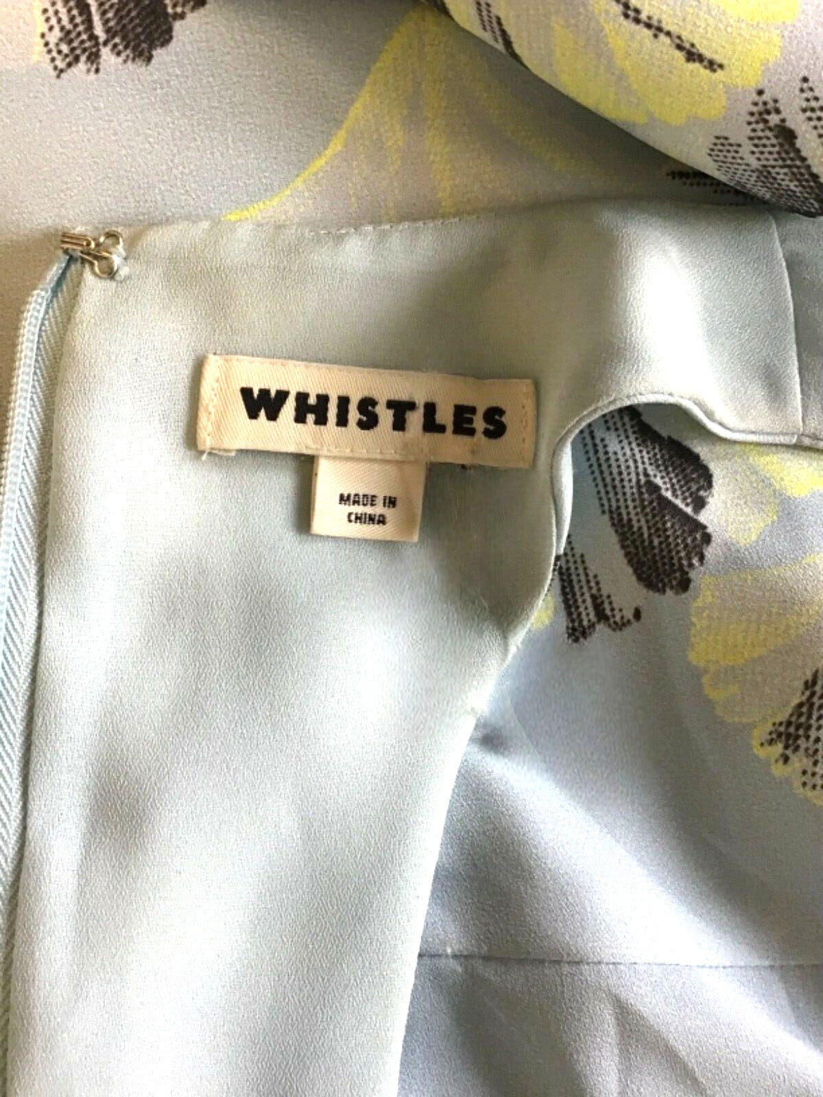 Close-up of a garment with 'Whistles' brand label on a floral background